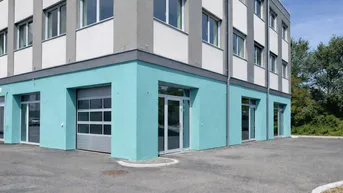 Modernes Geschäftsgebäude mit hellblauer Fassade im Erdgeschoss und großen Fenstern in den oberen Etagen.