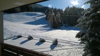 Panoramablick vom Balkon auf die weite, schneebedeckte Berglandschaft.