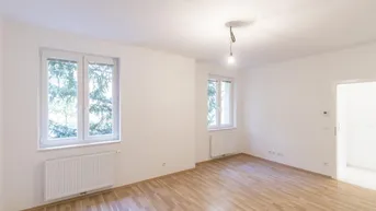 Helles, leeres Zimmer mit Parkettboden und zwei Fenstern, bereit zur individuellen Gestaltung.