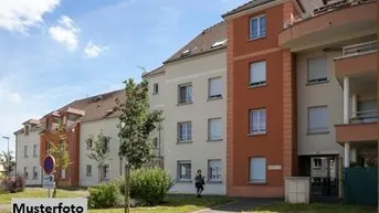 Mehrfamilienhaus mit moderner Architektur, Balkonen und gepflegter Grünfläche im Vordergrund.