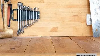 Eine gut organisierte Werkbank aus hellem Holz mit verschiedenen Werkzeugen, darunter ein Satz Schraubenschlüssel.