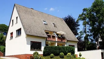 Freistehendes Einfamilienhaus mit Satteldach, kleinem Balkon und gepflegtem Vorgarten.