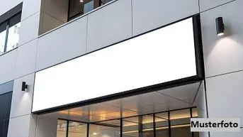 Moderne Gebäudefassade mit großen Fenstern und einem leeren Werbeschild über dem Eingangsbereich.