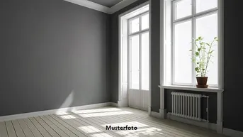 Heller Raum mit grauen Wänden, hellem Holzboden und großen Fenstern, die viel Tageslicht hereinlassen.
