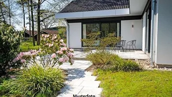 Moderne Terrasse mit Gartenmöbeln und blühenden Pflanzen in einem gepflegten Garten.