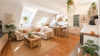 Heller offener Wohnbereich mit Holzboden, gemütlichem Sofa, Küche und Kamin unter Dachschrägen.