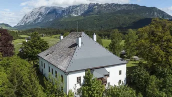 Großes Anwesen mit traditionellem Dach und beeindruckendem Bergblick in ländlicher Umgebung.
