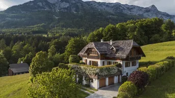Idyllisches Landhaus in den Bergen mit traditionellem Holzdach und gepflegter Auffahrt.