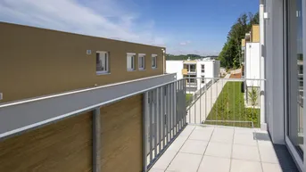 Heller Balkon mit Fliesenboden und Metallgeländer, mit Blick auf die umliegenden Gebäude und Grünflächen.