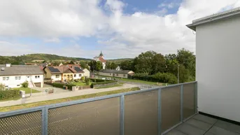 Balkon mit Blick auf die umliegende Landschaft und ein Dorf mit Kirche.