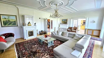 Großzügiges Wohnzimmer mit Stuckdecke, Kamin und elegantem Parkettboden, eingerichtet mit klassischen Möbeln.