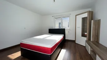 Helles Schlafzimmer mit Holzboden, einem Bett und einem Kleiderschrank am Fenster.