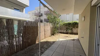 Große geflieste Terrasse mit Sonnenschutz und kleinem Gartenbereich, umgeben von einem Bambuszaun.
