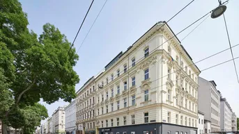 Historisches Eckgebäude mit reich verzierter Fassade an einer belebten Straße in der Stadt.