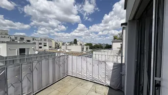 Geräumige Dachterrasse mit Fliesenboden und Blick auf die umliegenden Gebäude unter blauem Himmel.