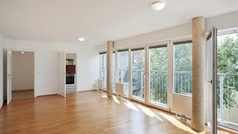 Helles und geräumiges Wohnzimmer mit Parkettboden, großen Fenstern und Zugang zum Balkon.