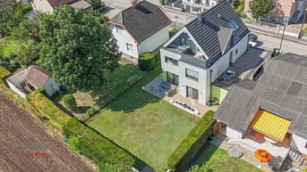Luftaufnahme des modernen Hauses mit großem Garten und angrenzendem Feld.