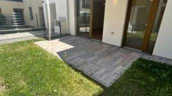 Geräumige Terrasse mit Steinplatten und angrenzender Rasenfläche, ideal für entspannte Stunden im Freien.