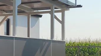 Außenansicht des Gebäudes mit überdachtem Bereich und Satellitenschüssel vor ländlicher Kulisse.