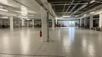 Geräumiger Gewerbebereich mit quadratischen Bodenfliesen, vielen Säulen und offener Deckenkonstruktion.