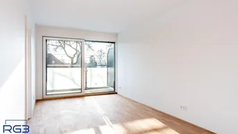 Helles Zimmer mit Holzboden und Zugang zu einem Balkon, ideal als Wohn- oder Schlafbereich.