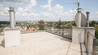 Große Dachterrasse mit Fliesenboden, Glasgeländer und weitem Blick über die Stadt.