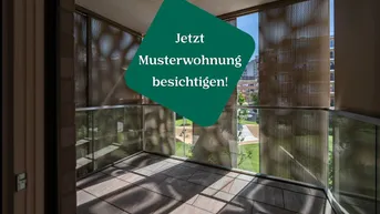 Helle Loggia mit Fliesenboden, Glasbrüstung und Blick auf eine Grünfläche sowie Stadtgebäude.