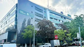 Großes Bürogebäude mit moderner Fassade und vielen Fenstern unter bewölktem Himmel.