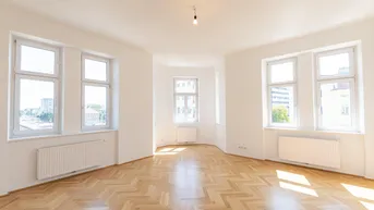 Helles, leeres Zimmer mit Fischgrätparkett und mehreren Fenstern, das viel Tageslicht hereinlässt.
