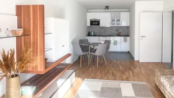 Offener Wohnbereich mit integrierter Küche, Esstisch und Holzboden, hell und modern gestaltet.