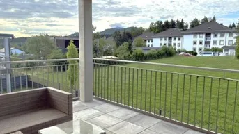 Geräumige Terrasse mit bequemen Outdoor-Möbeln und Blick ins Grüne sowie auf umliegende Gebäude.