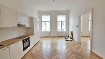 Helle, offene Wohnküche mit neuem Einbauküchenblock, Fischgrätparkett und hohen Decken mit Stuckelementen.