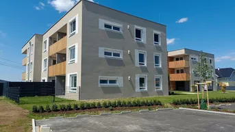 Moderne Wohngebäude mit Balkonen und gepflegter Außenanlage unter blauem Himmel.