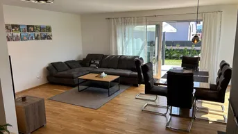 Heller Wohn- und Essbereich mit Holzboden, bequemer Sitzecke und direktem Zugang zur Terrasse.