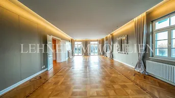 Großzügiges Wohnzimmer mit Fischgrätparkett, hohen Decken und bodentiefen Fenstern.