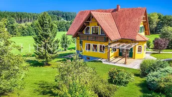Großzügiges Einfamilienhaus mit gelber Fassade, rotem Ziegeldach und weitläufigem Garten in ländlicher Umgebung.