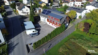 Luftaufnahme des Anwesens mit Photovoltaikanlage auf dem Dach und großem Vorplatz.