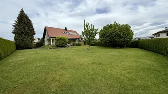 Großzügiger Gartenbereich mit gepflegtem Rasen und Hecken, umgeben von Bäumen und dem Einfamilienhaus.