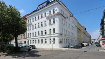 Eckgebäude mit frisch renovierter Fassade und modernem Dachausbau in urbaner Umgebung.