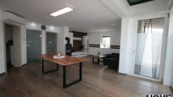 Geräumiger Wohn- und Essbereich mit Holzboden, Kaminofen und viel Tageslicht.