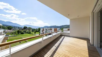 Geräumiger Balkon mit Holzboden und weitem Blick auf die umliegende Landschaft und Berge.