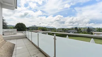 Große Terrasse mit Glasgeländer und Panoramablick auf die Berge und Landschaft.