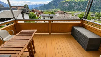 Geräumiger Balkon mit Holzboden, Esstisch und beeindruckendem Bergblick in sonniger Lage.