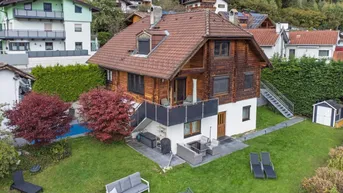 Großzügiger Gartenbereich mit Pool, Terrasse und Sitzgelegenheiten, umgeben von grüner Landschaft und Bergen.