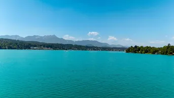 Panoramablick auf den weiten See mit Bergen und bewaldeten Ufern in der Ferne.