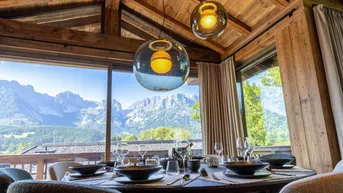 Eleganter Essbereich mit Bergblick durch große Fenster und stilvoller Beleuchtung.