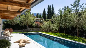 Terrasse mit Pool und Bergblick, umgeben von grüner Natur und Bäumen.