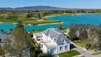 Luftaufnahme der luxuriösen Villa am Seeufer mit angrenzendem Golfplatz und malerischer Landschaft.