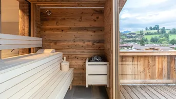Private Sauna mit Holzbänken und Panoramablick auf die grüne Berglandschaft.