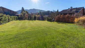 Sonniges Grundstück mit weitläufiger Rasenfläche und Bergblick in ländlicher Umgebung.